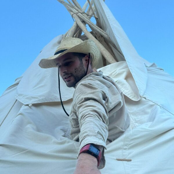 Tipiaufbau_ Mann schaut aus dem Tipi
