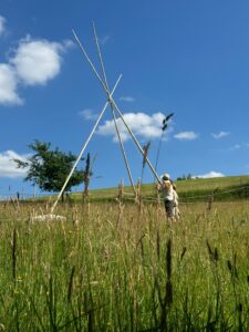 Tipi im Aufbau ,Stangen auf der Wiese