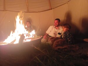 Menschen sitzen am Lagerfeuer im Tipi