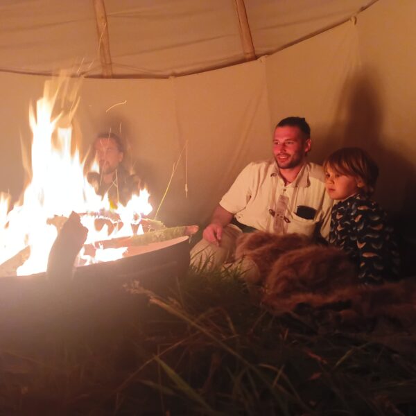 Menschen sitzen am Lagerfeuer im Tipi